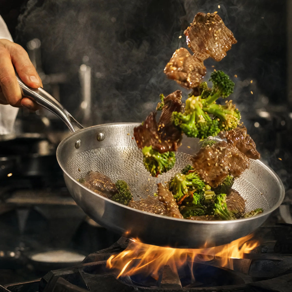 Titanium wok tossing beef and broccoli over a high flame