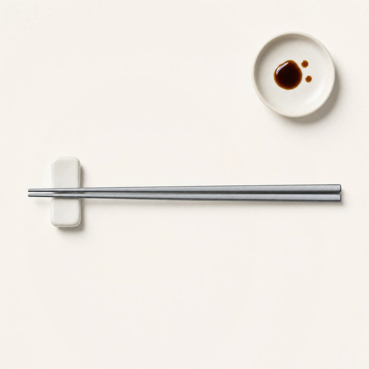 A pair of titanium chopsticks on a ceramic chopstick rest