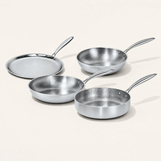 Pure titanium hammered frying pan, deep pan, wok and crepe pan on a cream background