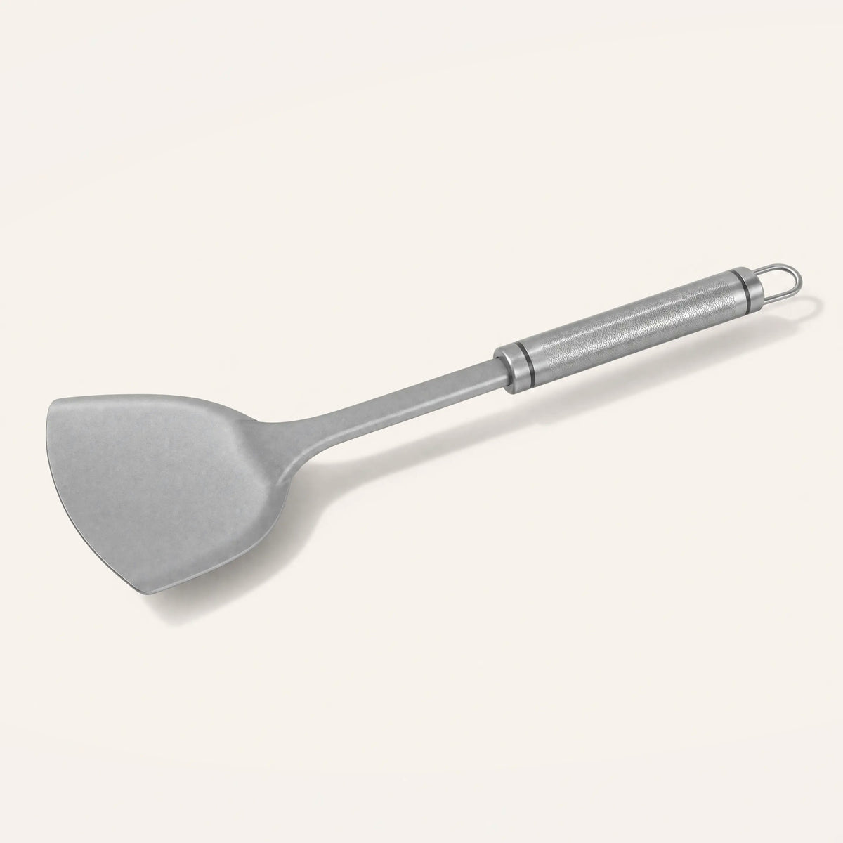 Pure titanium spatula on a cream background